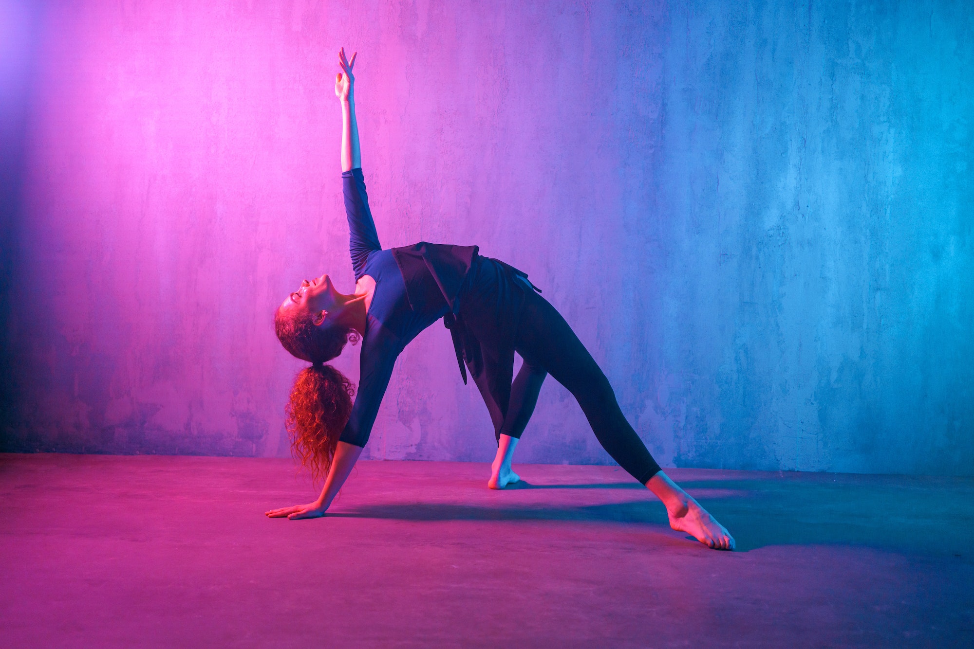 Modern dance girl dancer dancing in neon light doing gymnastic exercises in studio, copy space.